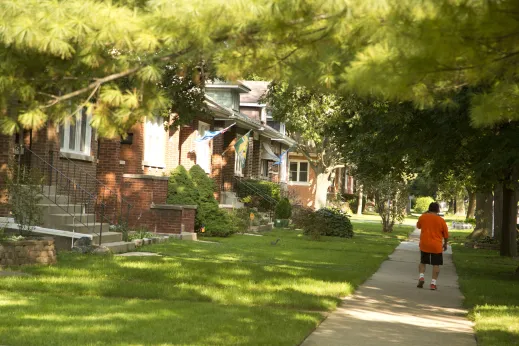 Man walking on sidewalk in tree shade in North Mayfair