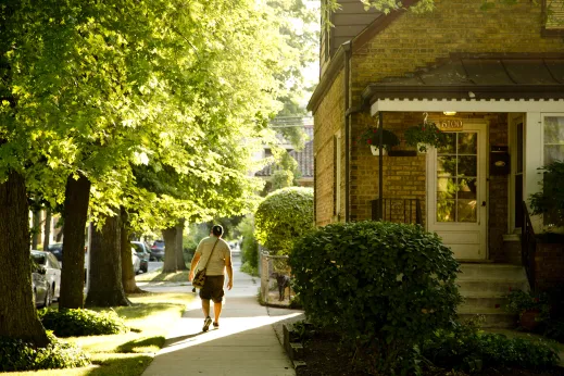 Man walking on sidewalk next to single family home in West Ridge Chicago