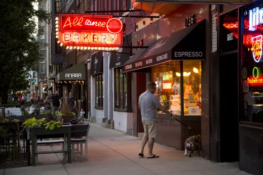 Man with dog outside Alliance Bakery neon sign in Wicker Park Chicago