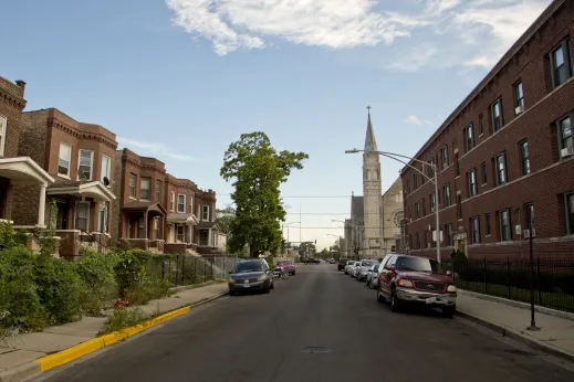 Neighborhood street with apartments and church steeple in background in West Garfield Park Chicago