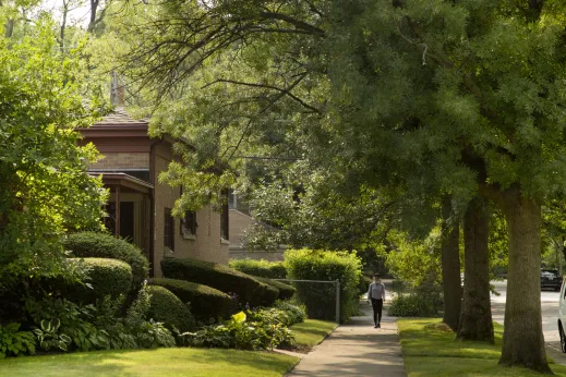 Pedestrian strolling down sidewalk near house in Peterson Park