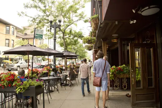 Pedestrians and restaurant patrons in outdoor patio seating neighborhood pub in Lakeview Chicago