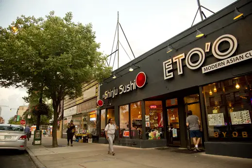 Pedestrians outside Shinju Sushi restaurant entrance in Hyde Park Chicago