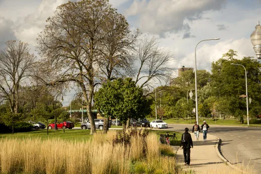 Pedestrians strolling by Garfield Park with apartments in background in East Garfield Park Chicago