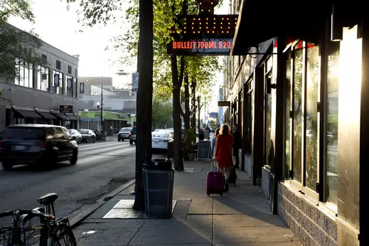 Pedestrians walk in front of local businesses in Logan Square Chicago