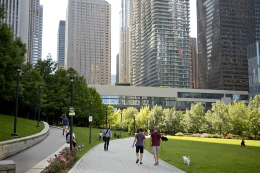 Pedestrians walking in green park near Aqua Tower in Lakeshore East Chicago
