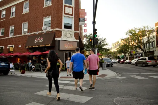 Pedestrians walking across intersection and Fork restaurant entrance in Lincoln Square Chicago