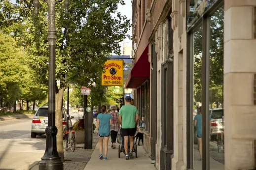 Pedestrians walking on sidewalk by Simmons Pro Shop sign in St. Ben's Chicago