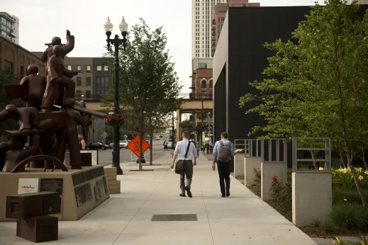 Pedestrians walking on sidewalk by sculpture in Fulton Market Chicago