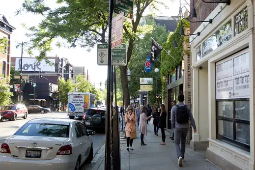 Pedestrians walking by sidewalk sports bar front in Lincoln Park