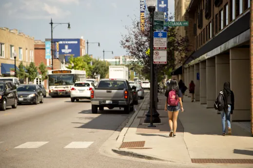 Pedestrians walking on sidewalk by traffic on W Foster Ave in North Park Chicago