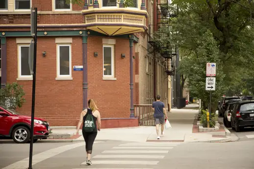 People crossing street on crosswalk by apartments in East Village Chicago