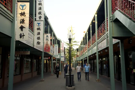 People walking in New Chinatown Square with shops and walkways