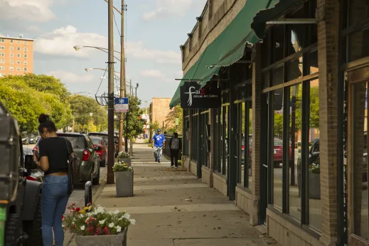 People walking by local businesses and retail shops by apartments in Oakland Chicago