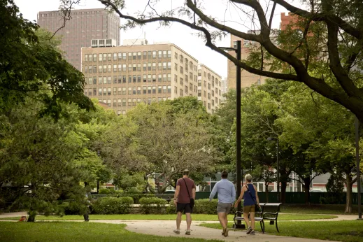 People walking in public park with trees and apartments in the background in Dearborn Park Chicago