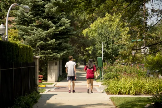 People walking on sidewalk by gardens in Margate Park Chicago