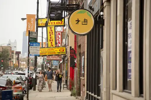 People walking and taking selfies on sidewalk by local businesses in East Village