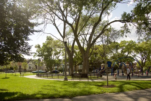 Public park playground with families playing and houses in the background in Peterson Woods