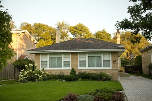 Split level ranch style house exterior and lawn with paved driveway in Sauganash