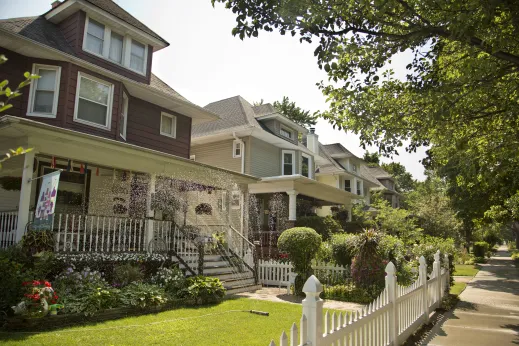 Sprinkler on front lawns with white picket fence house in Portage Park Chicago