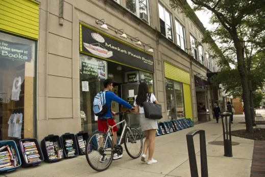 Students walking their bikes in front of Market Fresh Books in Evanston, IL