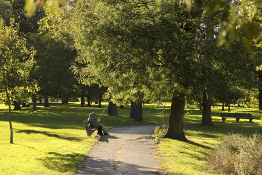 Two people sitting on park bench with fishing poles in Washington Park Chicago