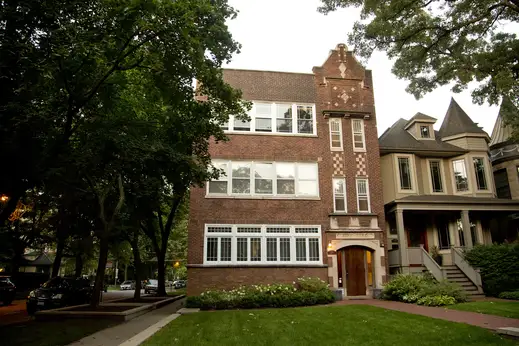 Vintage brick apartment building beside Victorian style house and front yard in Graceland West