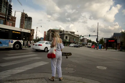 Woman on longboard at the intersection of Fullerton Ave and Halsted St in DePaul