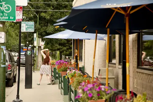 Woman walking dog near restaurant outdoor patio in East Village Chicago