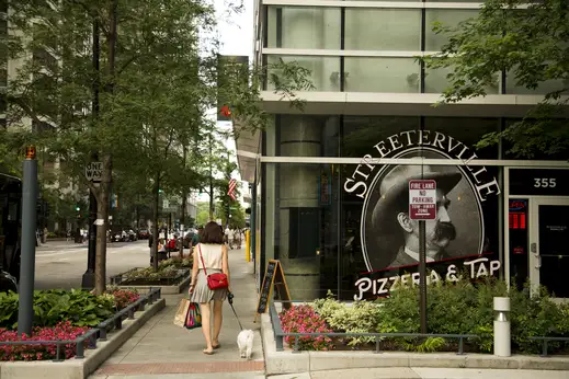 Woman walking small dog outside Streeterville Pizzeria restaurant in Streeterville Chicago