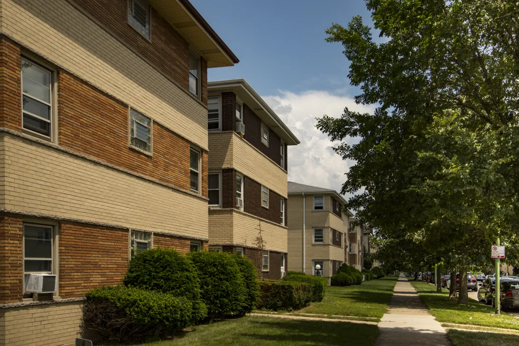 three story apartment brick buildings with shrubs in front and cars on street in the O’Hare neighborhood of Chicago