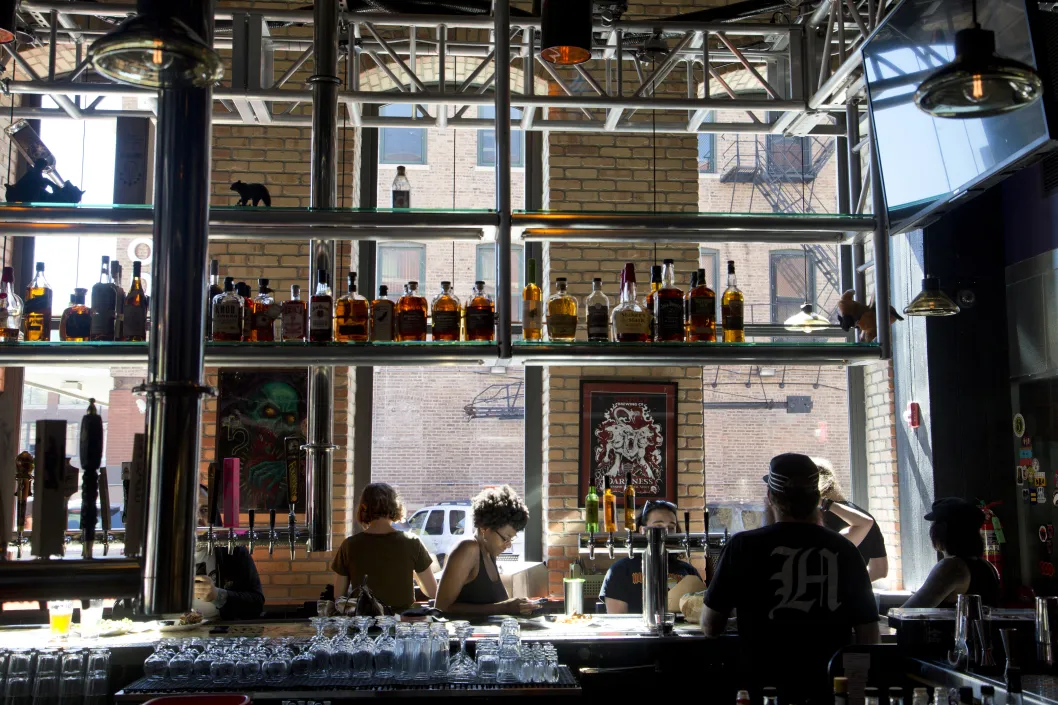 Bar interior with patrons, spirits, and shelf windows in the West Loop Chicago