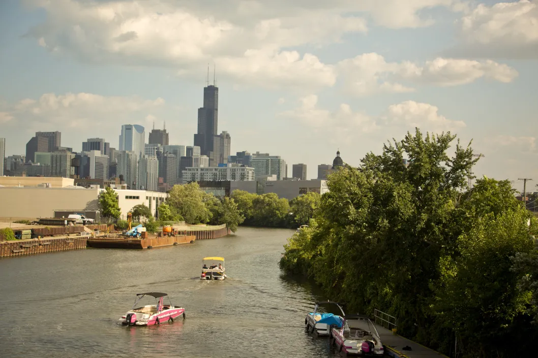 Boats cruising down Chicago River North Branch and Chicago skyline in River West
