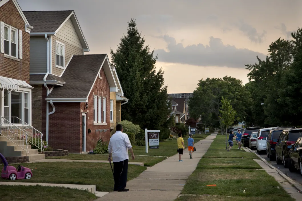 Boys playing with father watching on front lawns in West Ridge Chicago