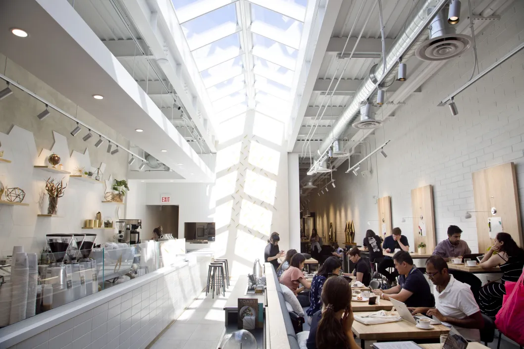 Coffee shop interior with skylight and white tile decor with customers seated in the West Loop