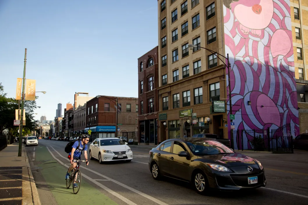 Cyclist riding in bike lane with mural in the background in Noble Square Chicago