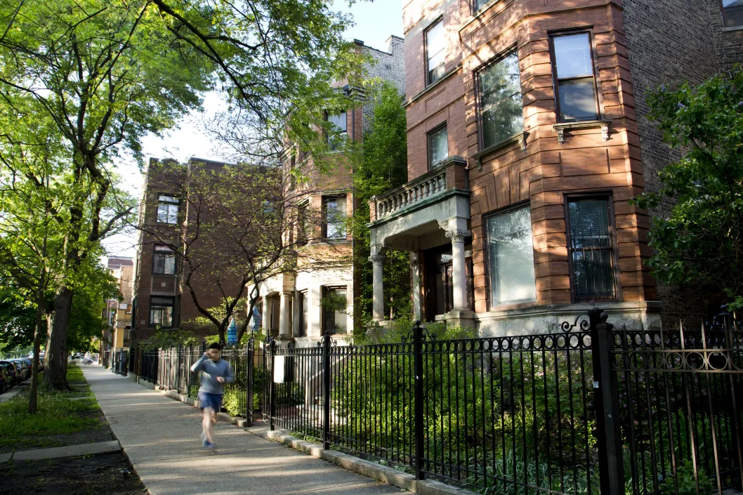 Jogger runs in front of wrought iron fences and apartment buildings in Logan Square Chicago