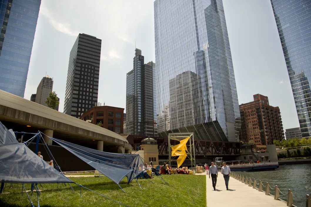 Pedestrians stroll on Chicago Riverwalk next to public artwork in the Chicago Loop
