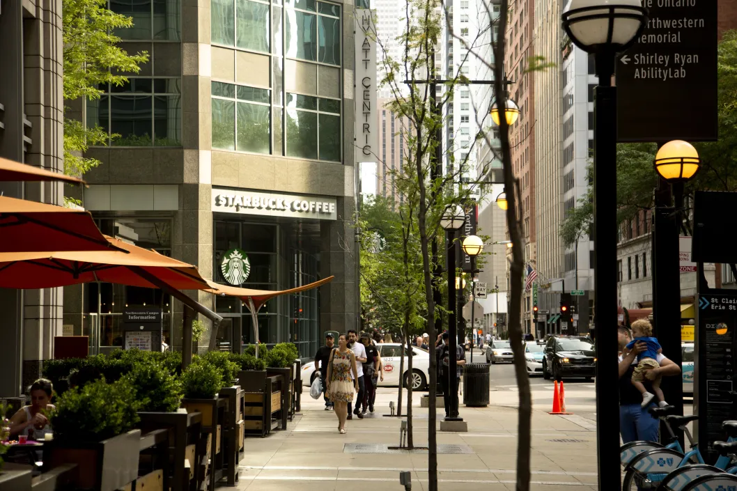 Pedestrians walking on sidewalk across from Starbucks on N St Clair St in Streeterville